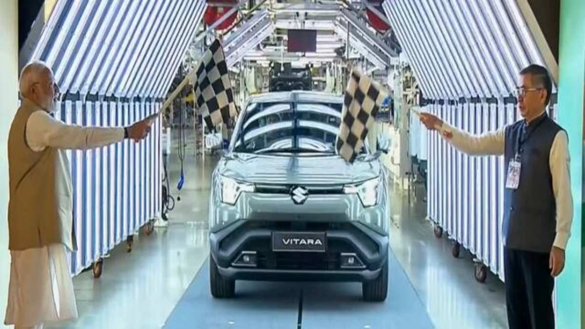 Maruti e Vitara electric SUV on display showing modern exterior styling, LED headlights, and Suzuki badging with Gujarat manufacturing plant in background Maruti e Vitara electric SUV on display showing modern exterior styling, LED headlights, and Suzuki badging with Gujarat manufacturing plant in background